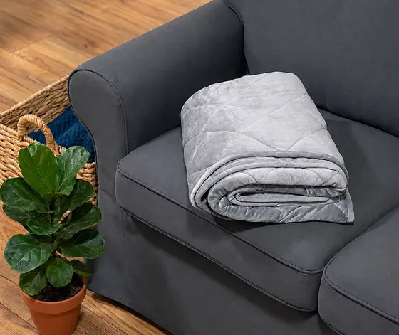 Official image of a folded grey Velin weighted blanket on a sofa